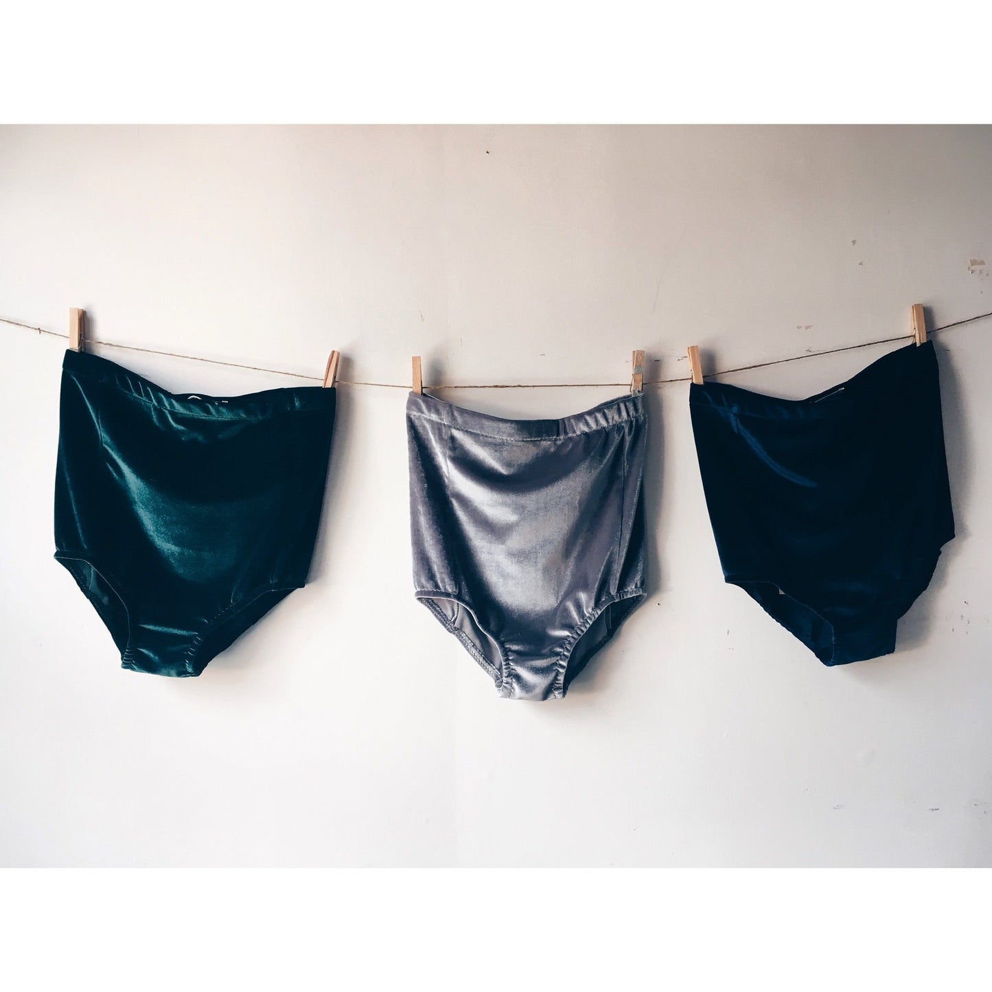 3 pairs of Velvet shorts pegged to a line against a white wall