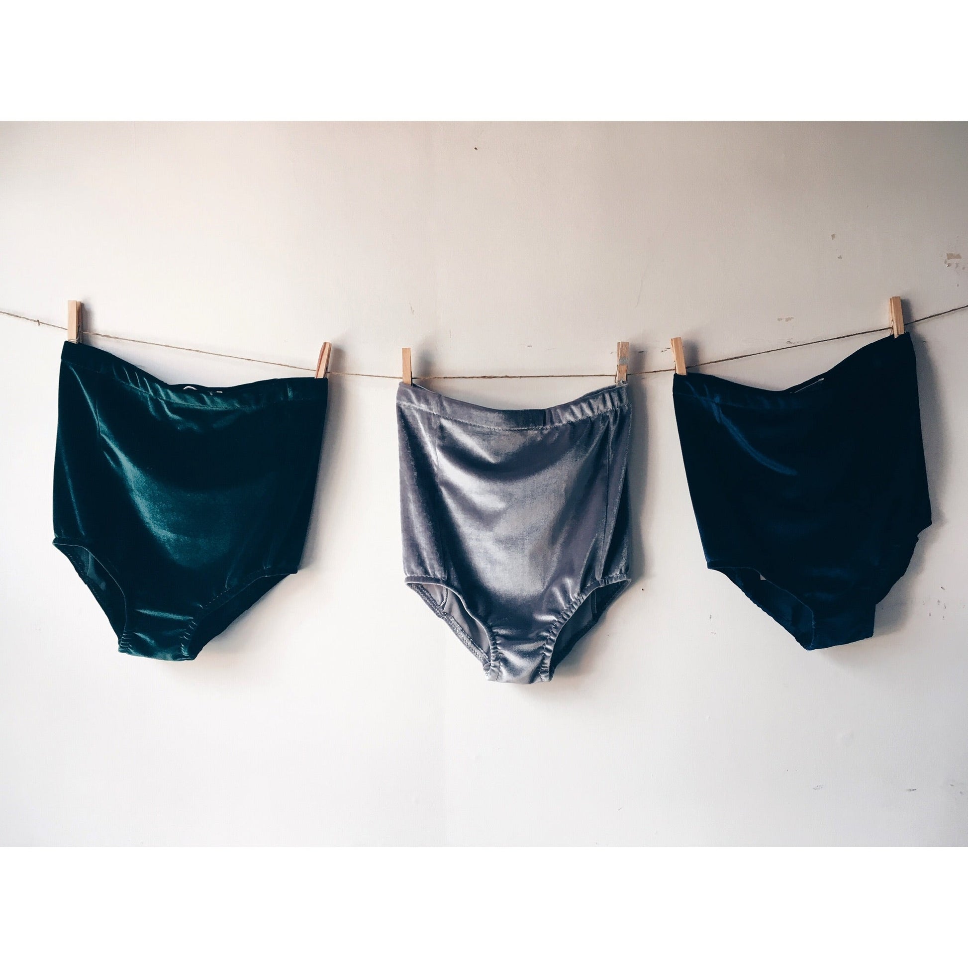 3 pairs of Velvet shorts pegged to a line against a white wall