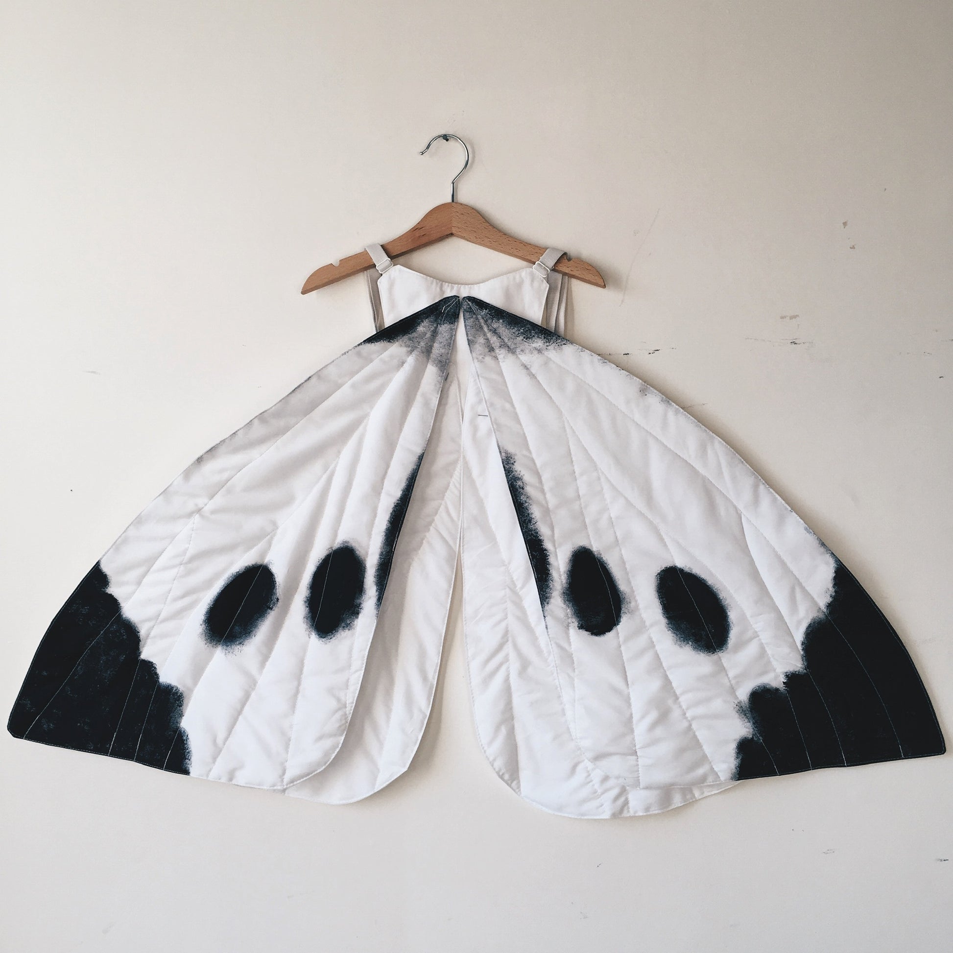 Cabbage white butterfly wings on a wooden hanger against a white wall
