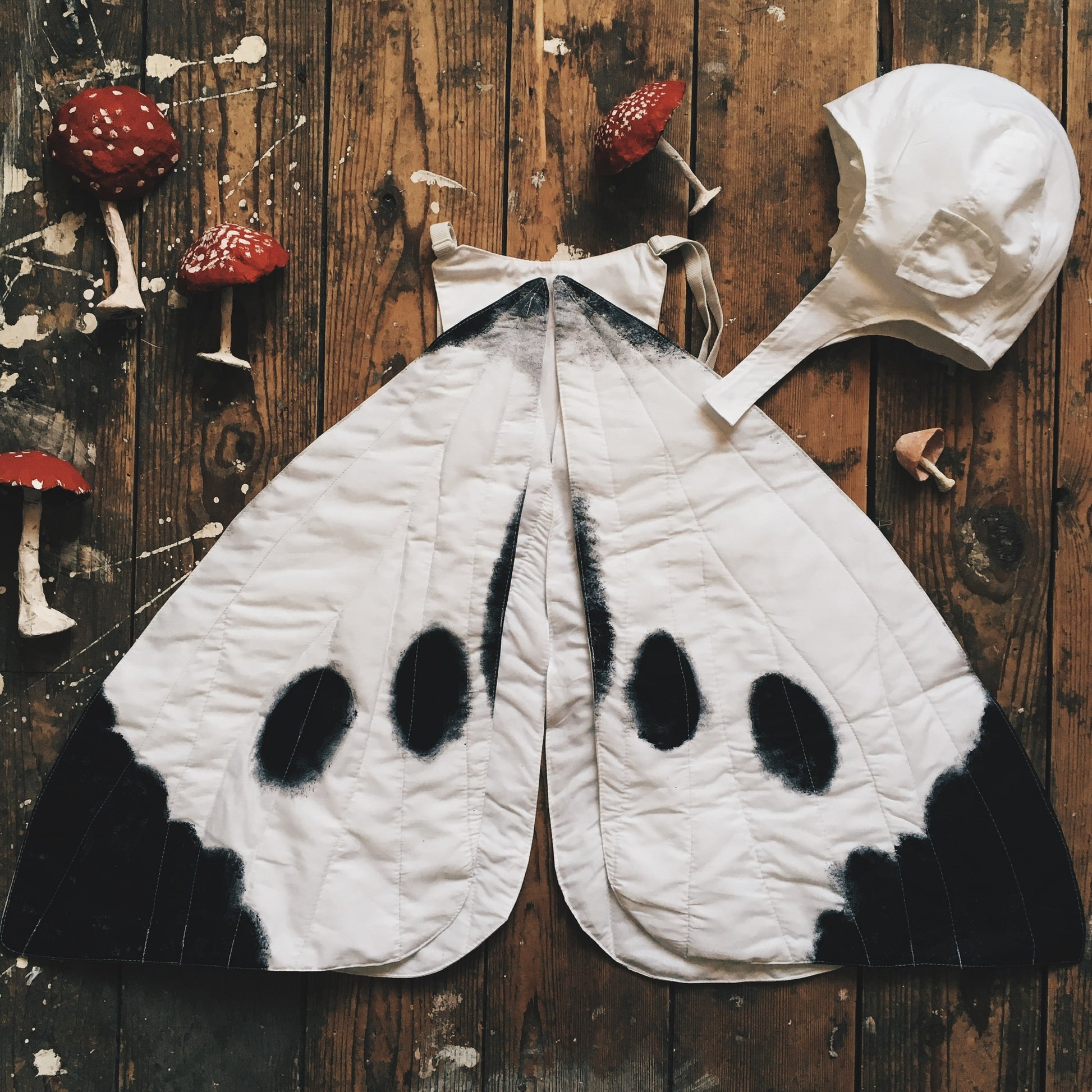 cabbage child's costume.  White butterfly wings and white flying hat placed on wooden floorboards