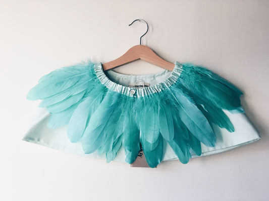 Mint green feather cape on wooden hanger against a white wall
