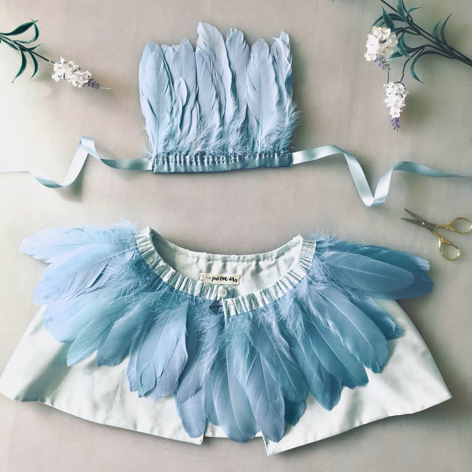 flat-lay of Pastel Blue feather cape and headdress by For Just ONE Day