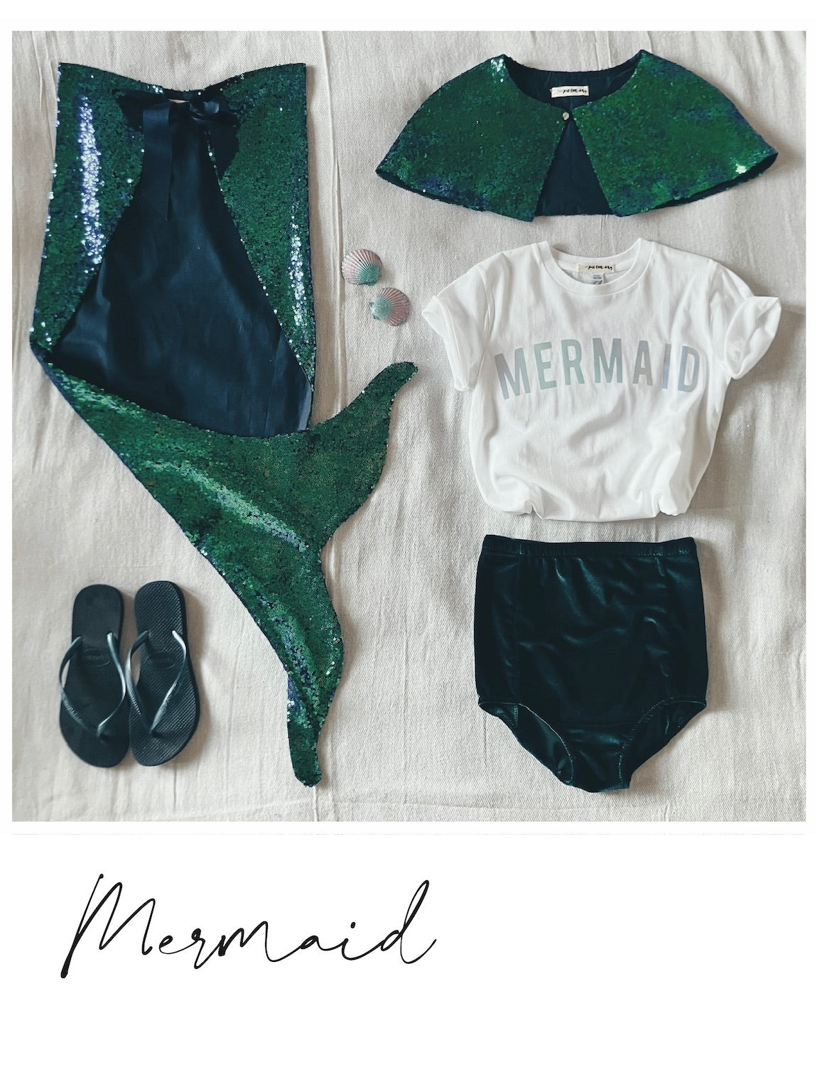 flat-lay of Childs mermaid costume, sequin tail, sequin cape, mermaid t-shirt, and velvet shorts by For Just ONE Day