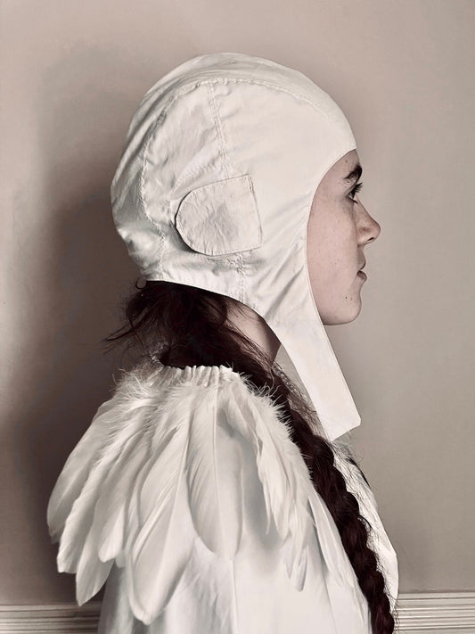 Side view of girl wearing a white flying hat and feather cape